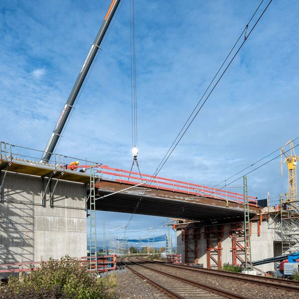 Zu sehen ist das Einheben der Stahlträger bei dem Bau der Eisenbahnüberführung