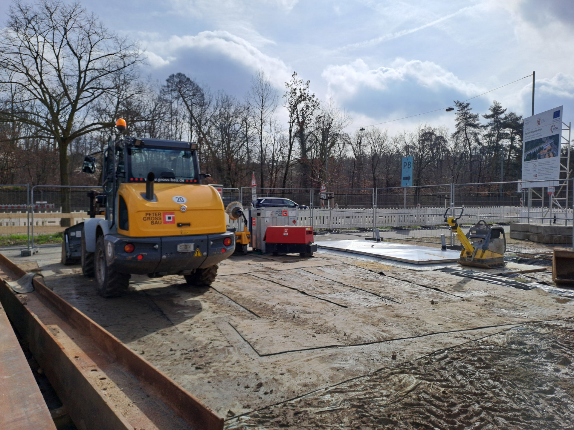 Kleiner Bagger steht auf Platten auf der Baustelle